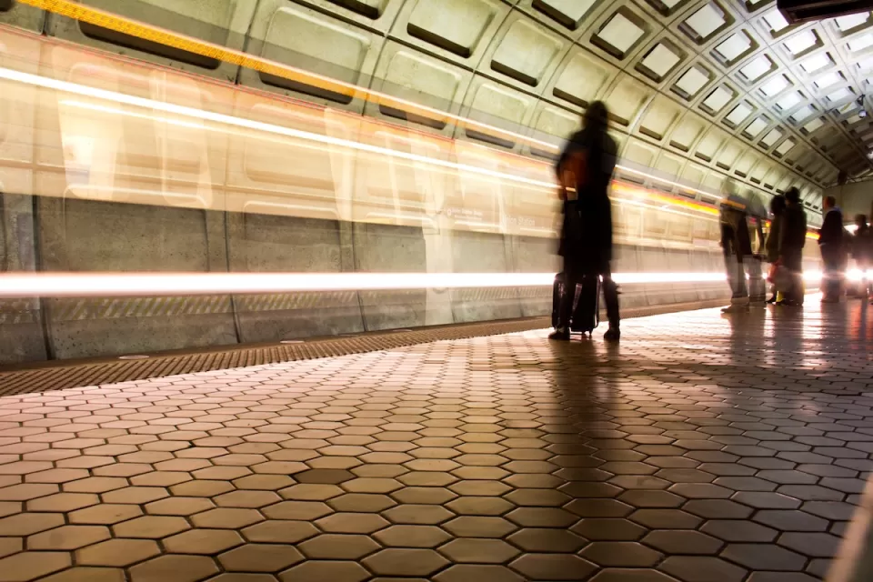 Washington DC Metro subway platform with passengers waiting and blurred train passing.